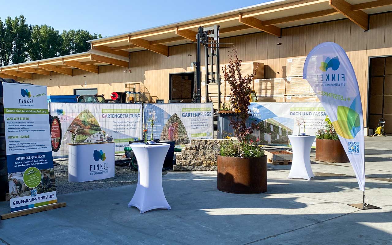 Outdoor-Messestand bestehehend aus Bauzaunbanner, einer Premium-Messetheke und Give-Aways